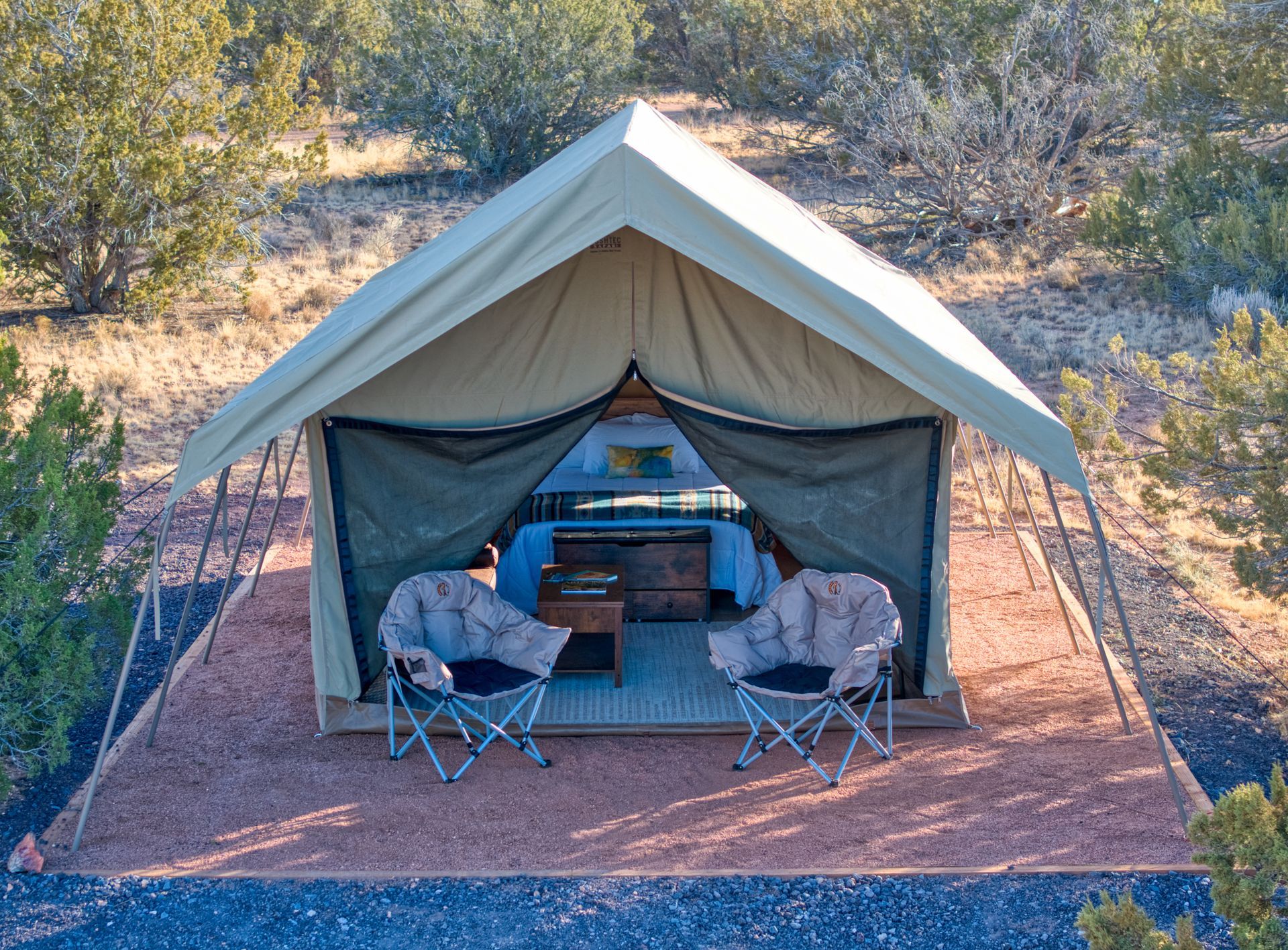 A small tent is sitting on top of a wooden platform in the middle of a field.