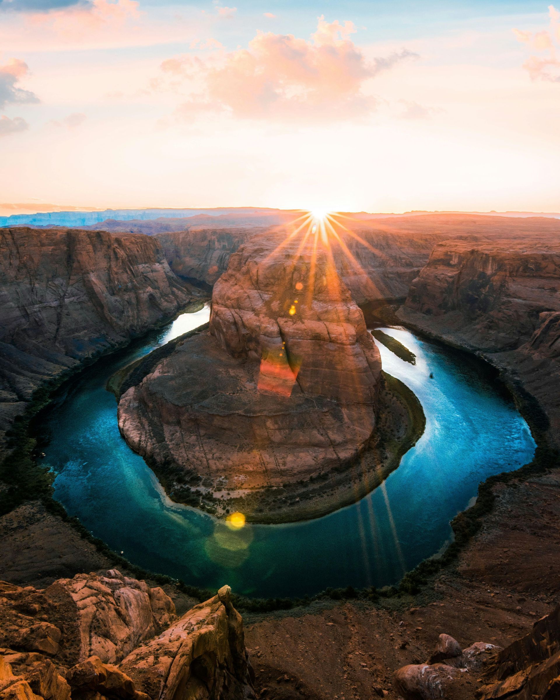 A large rock formation in the middle of a desert with a sunset in the background.