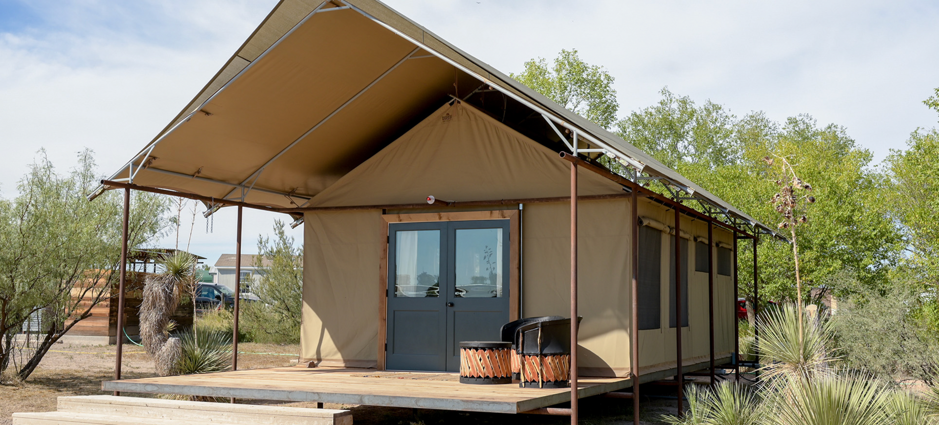 A small tent is sitting on top of a wooden platform in the middle of a field.