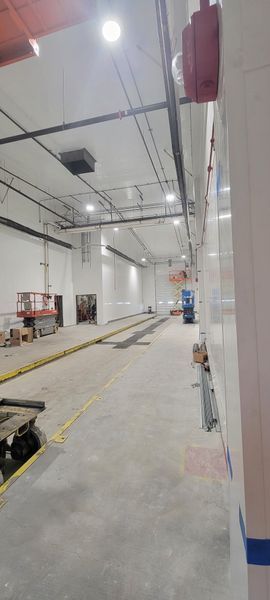 A large empty warehouse with a lot of lights on the ceiling.