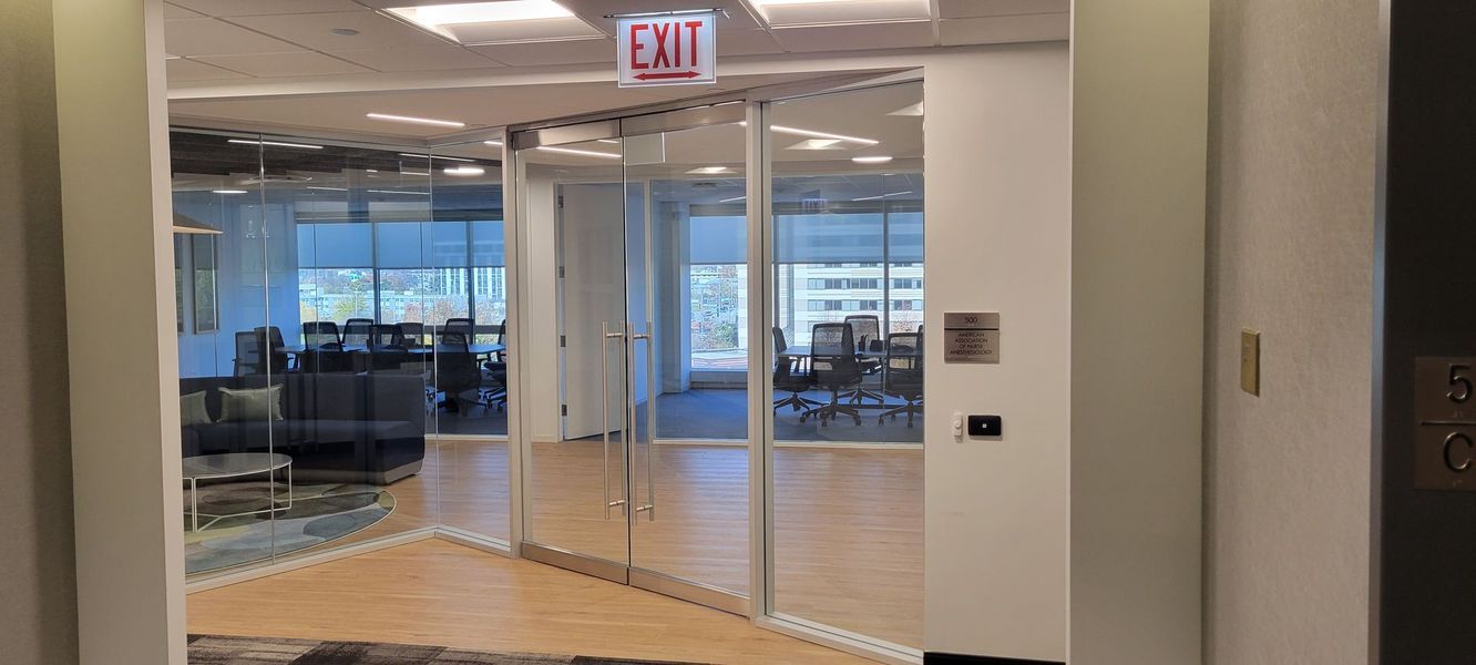A large empty room with a glass door and an exit sign.