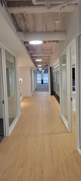 A long hallway with wooden floors and white walls in an office building.