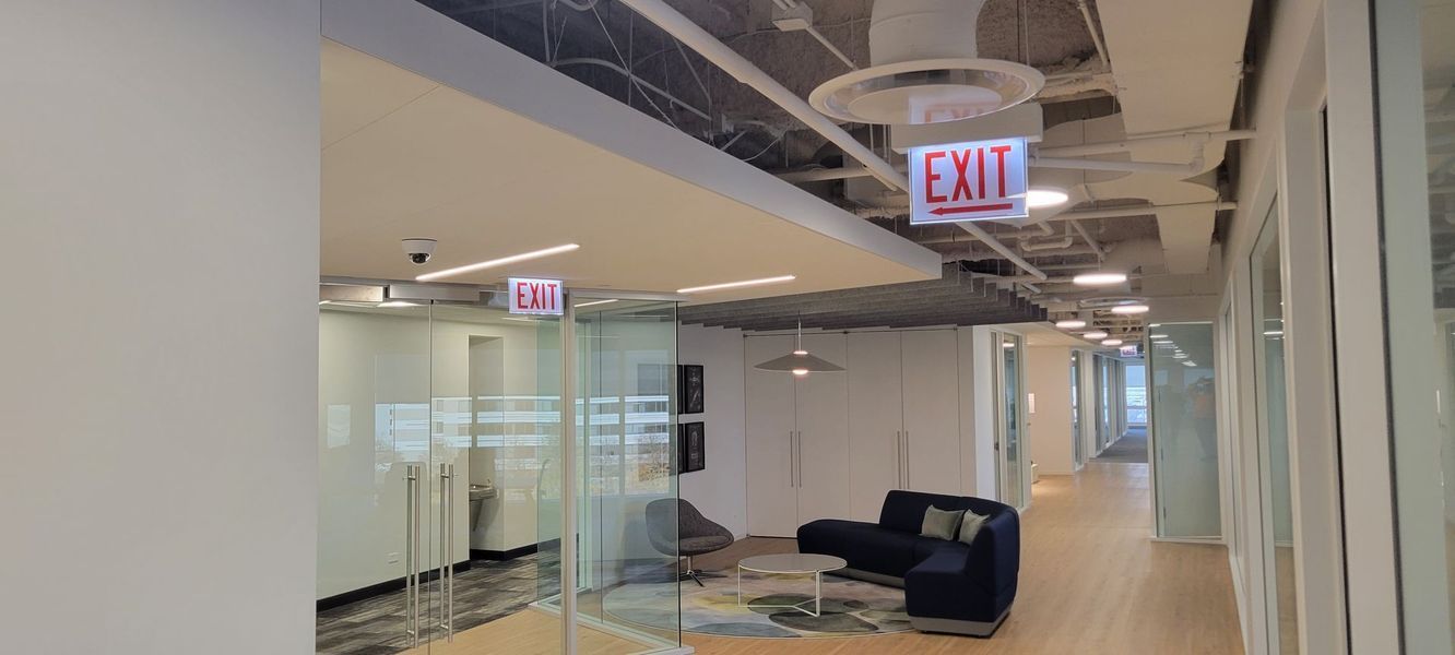 A long hallway with a red exit sign hanging from the ceiling.