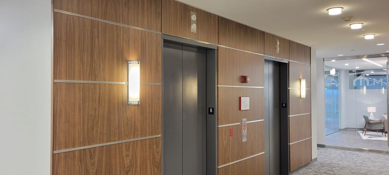 A hallway with two elevators and wooden walls.