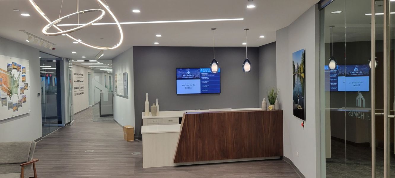 A lobby with a wooden desk and a television on the wall.