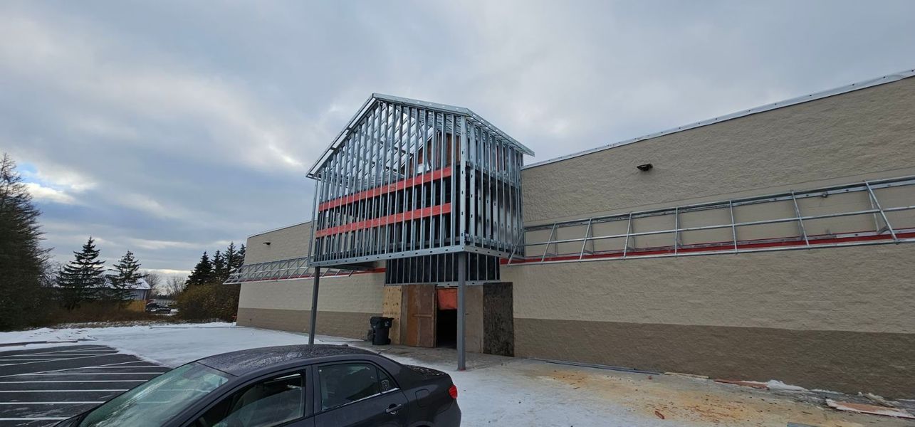 A car is parked in front of a building under construction.