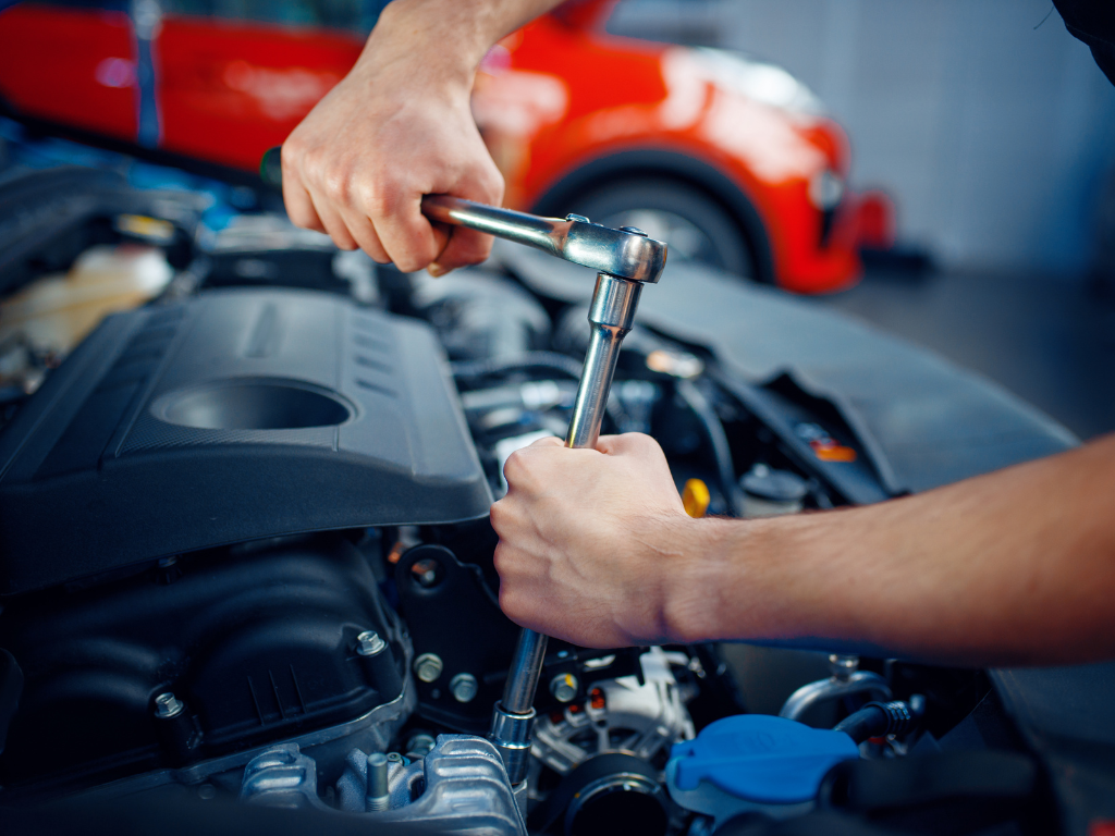 A man is working on a car engine with a wrench.