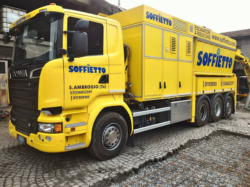 Un camion Scania giallo brillante, a più assi, con la scritta 