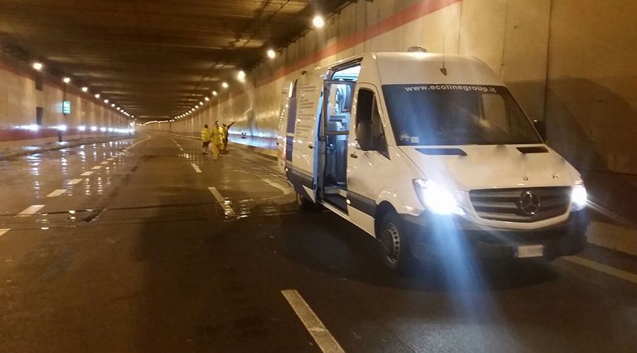 Un furgone Mercedes-Benz bianco con lo sportello laterale aperto è parcheggiato all'interno di una galleria ben illuminata, con degli operai nelle vicinanze.