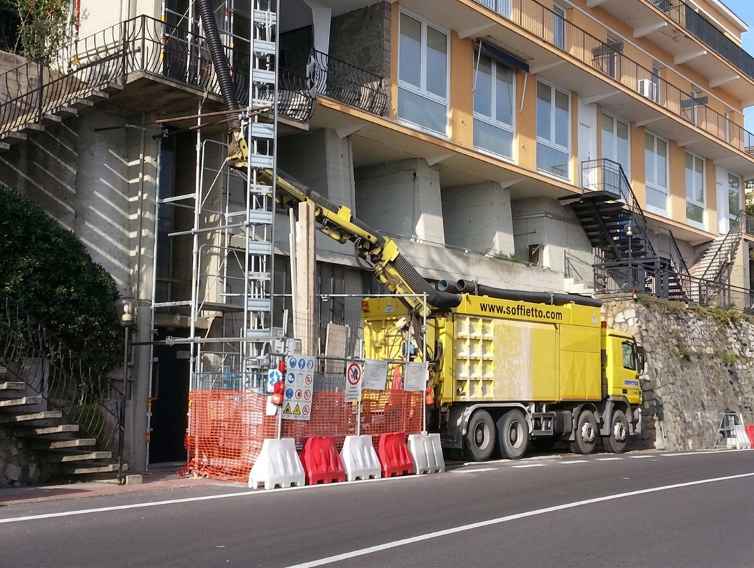 Una ripresa grandangolare degli interni, che mostra un grande tubo industriale dall'alto, con un tubo flessibile scuro che serpeggia verso una luce lontana.