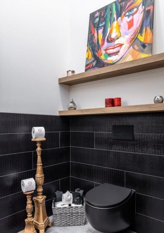 Une salle de bain avec un tableau d'une femme sur le mur au dessus des toilettes.