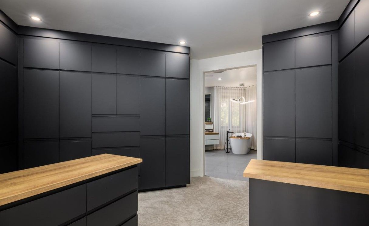 Un dressing avec des armoires noires et un comptoir en bois.