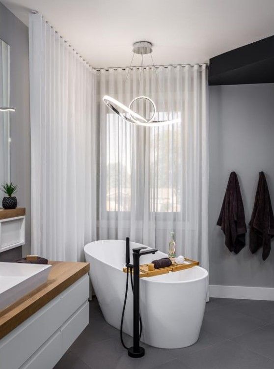 Une salle de bain avec baignoire, lavabo, miroir et rideaux.