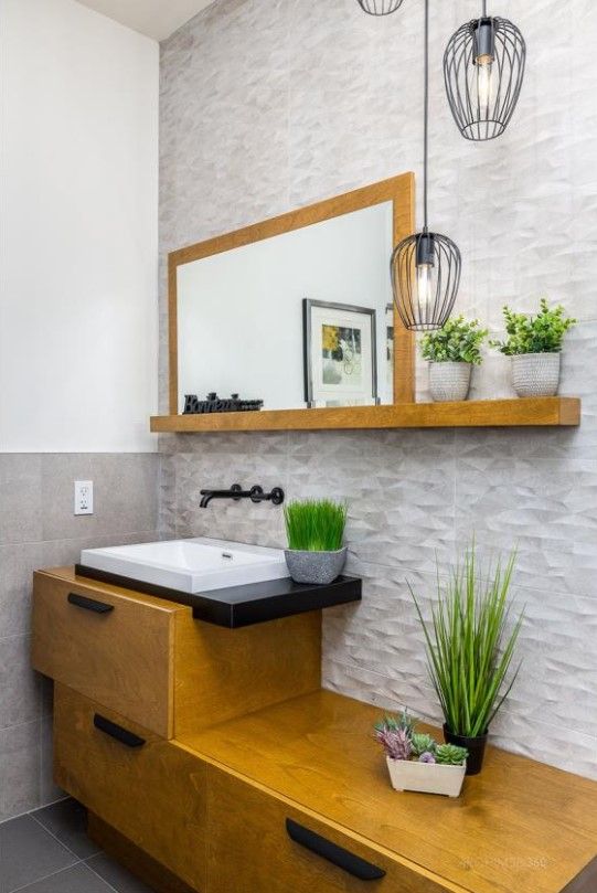 Une salle de bain avec un lavabo, un miroir, une étagère et des plantes.