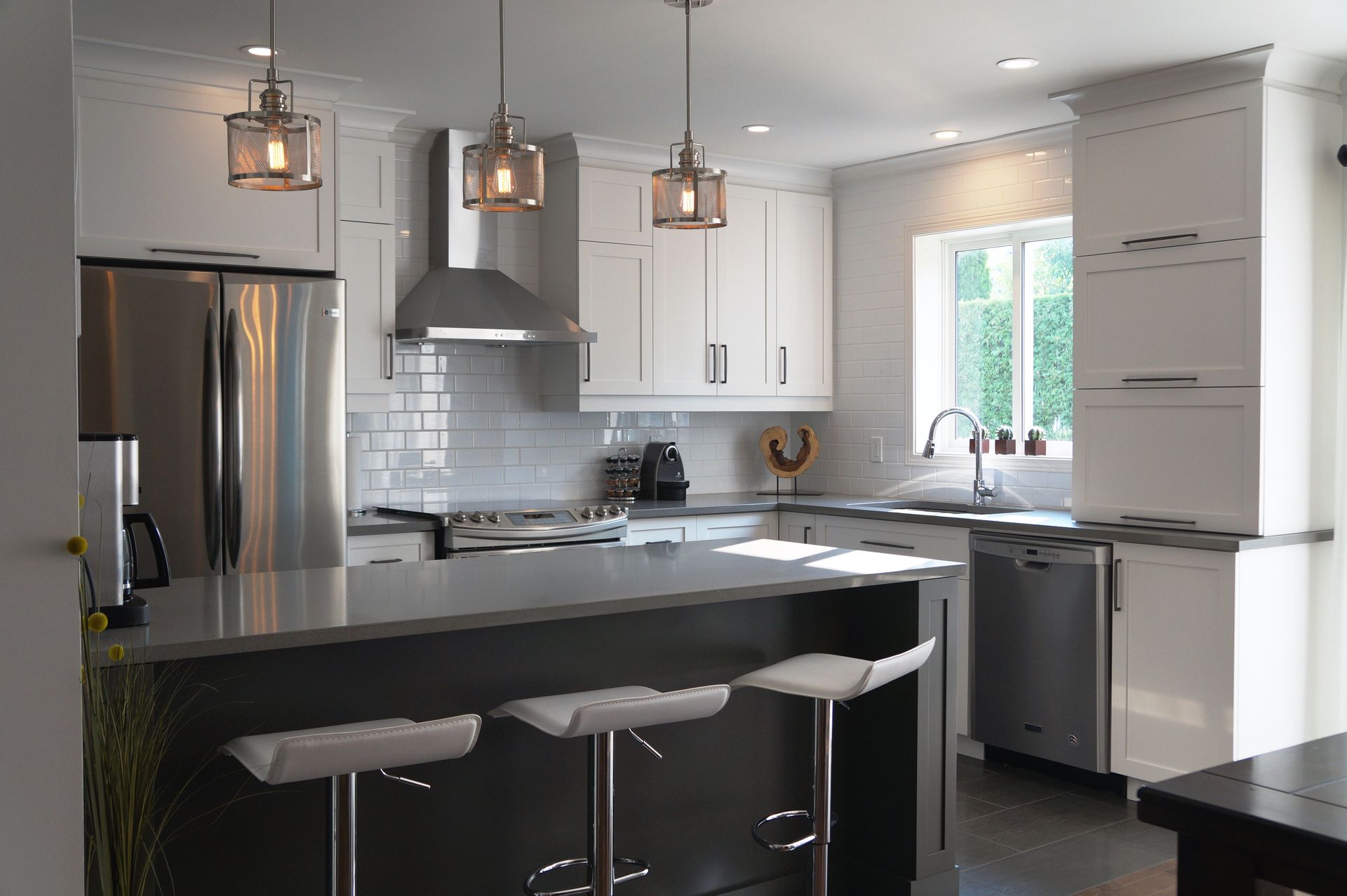 Une cuisine avec des armoires blanches, des électroménagers en acier inoxydable et un grand îlot.