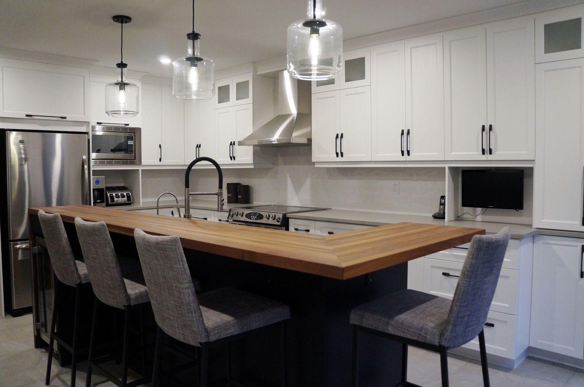 Une cuisine avec des armoires blanches, des électroménagers en acier inoxydable et un grand îlot.