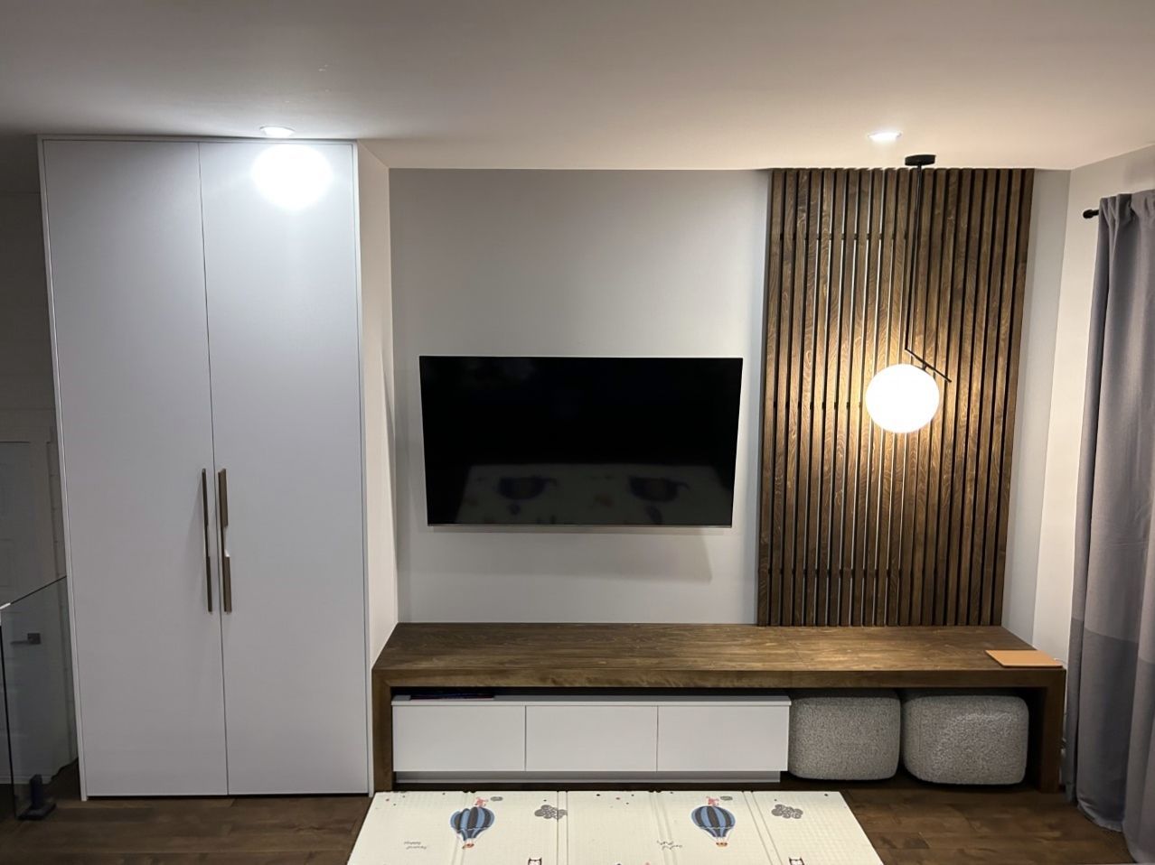 Un salon avec une télévision à écran plat au mur.