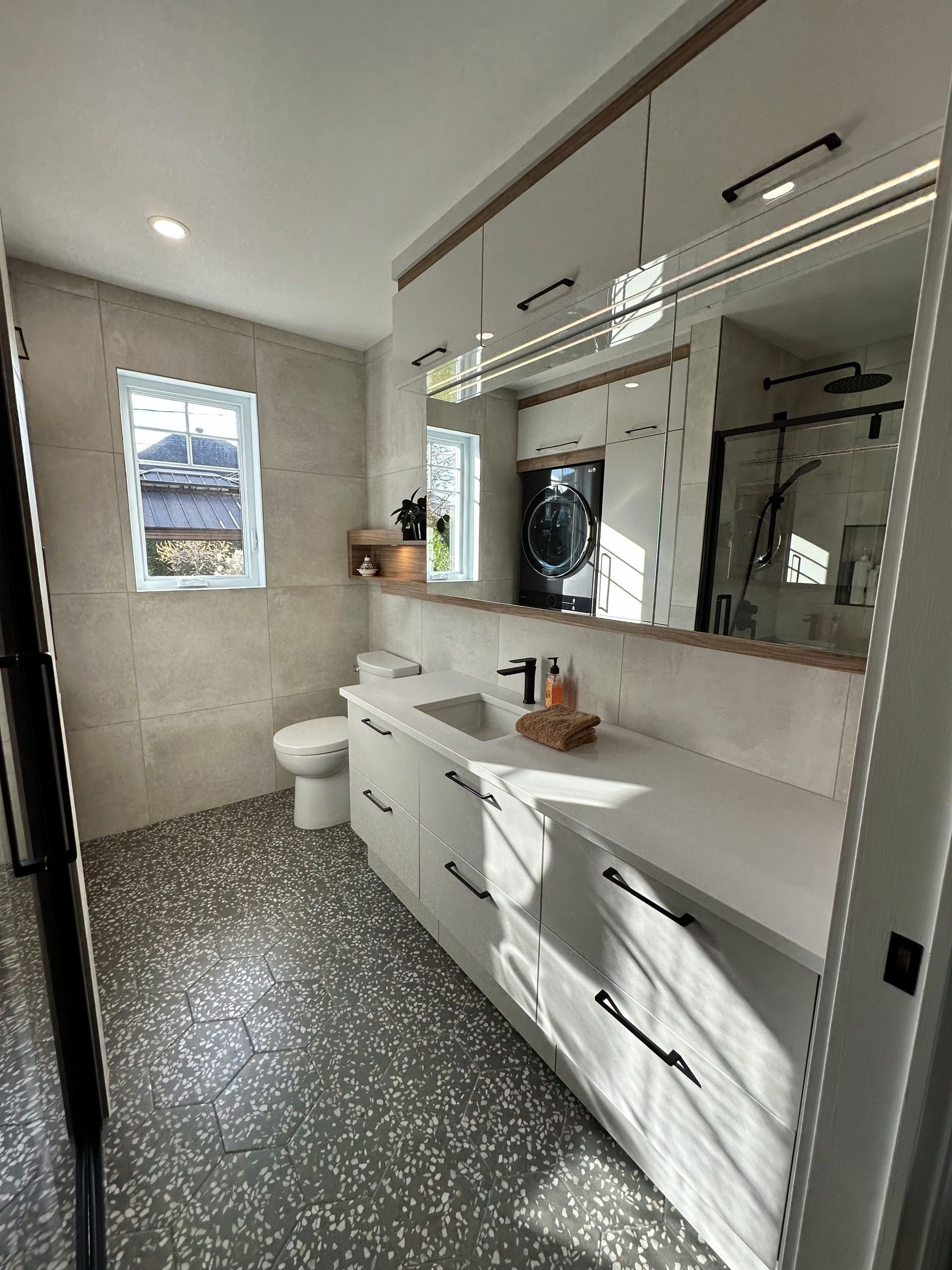 Une salle de bain avec WC, lavabo, miroir et fenêtre.