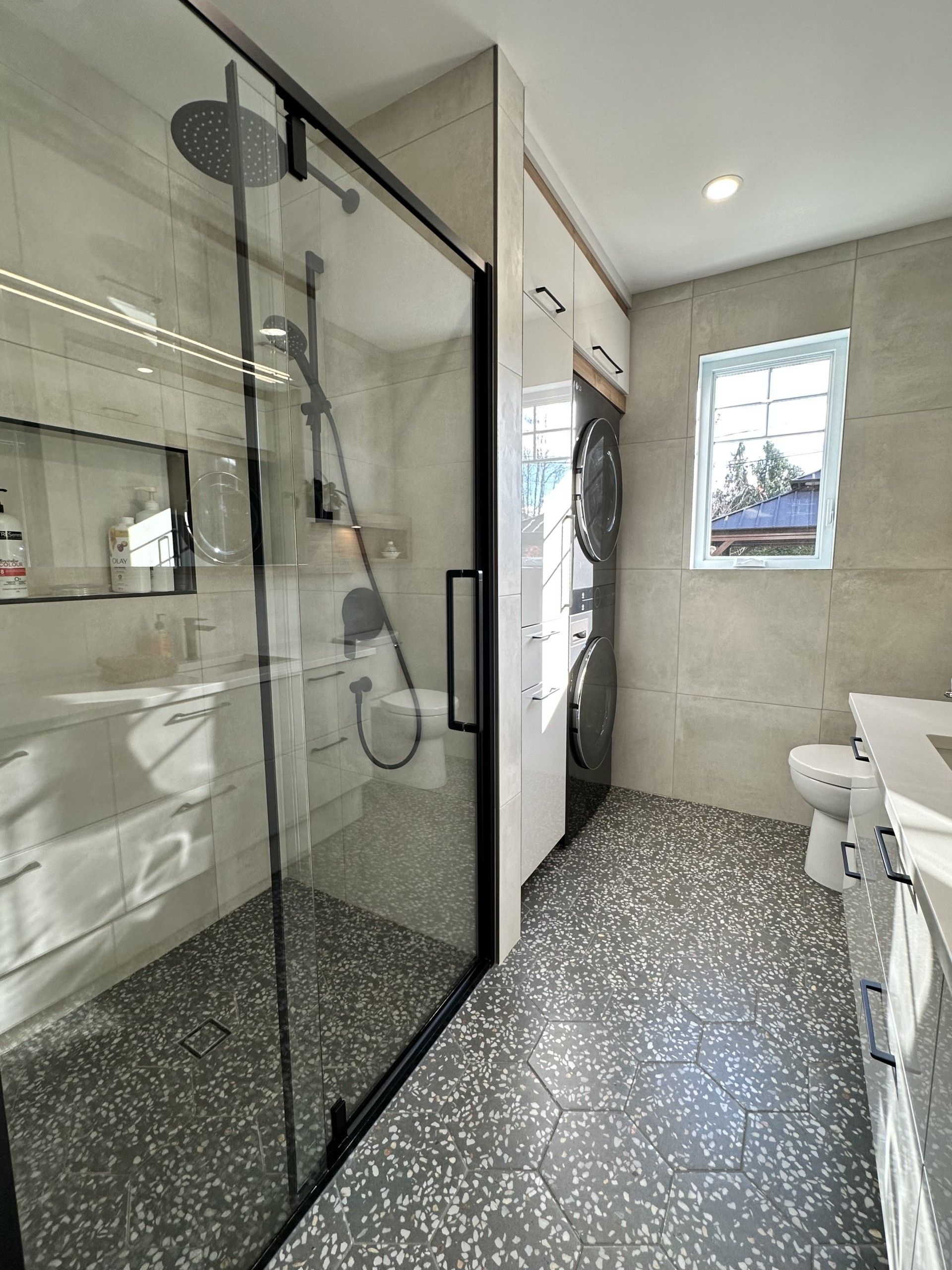 Une salle de bain avec douche à l'italienne, lavabo, WC et fenêtre.