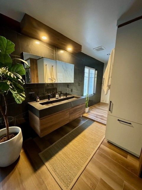 Une salle de bain avec deux lavabos et une plante en pot