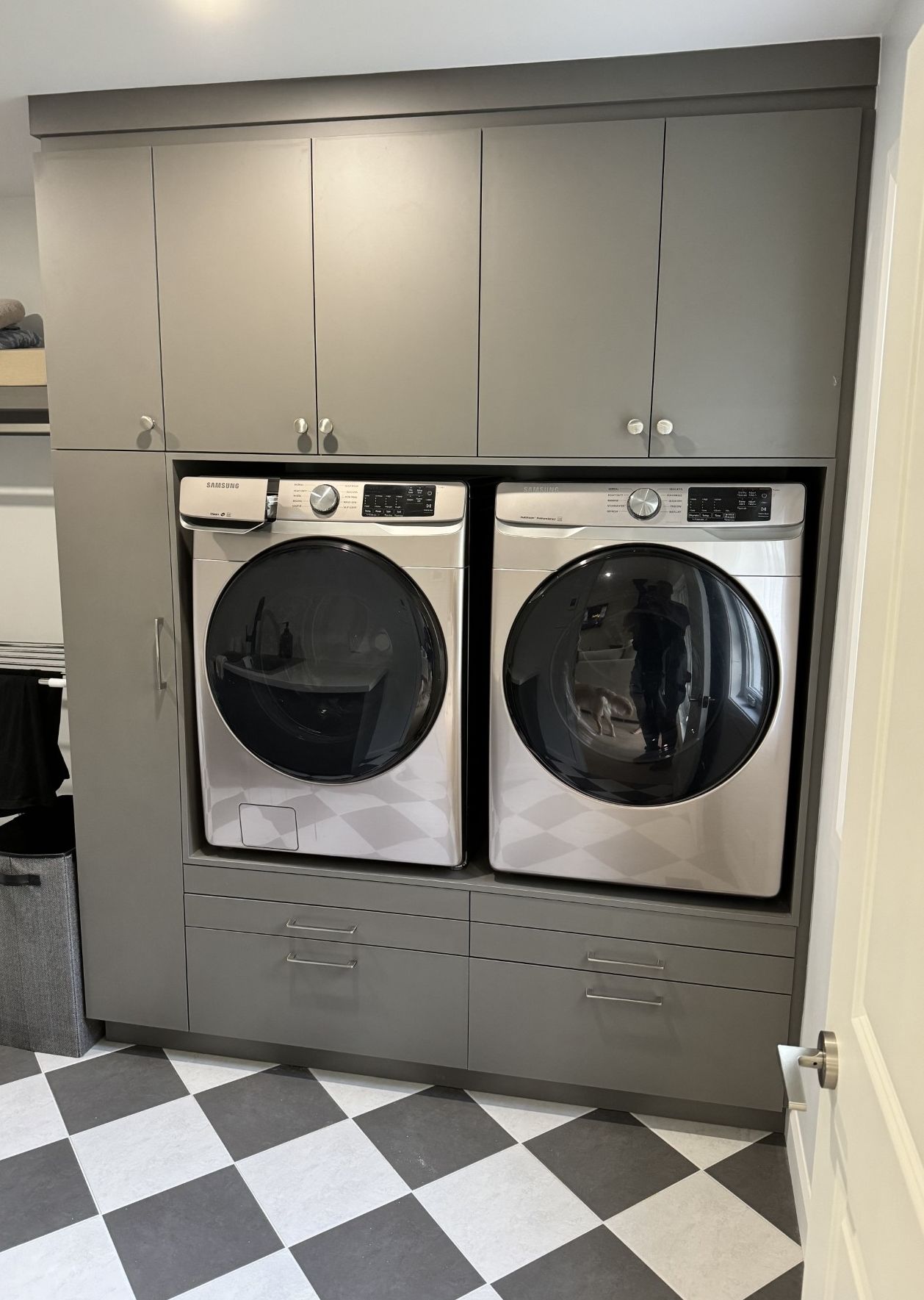 Une buanderie avec un sol en damier et deux laveuses et sécheuses.