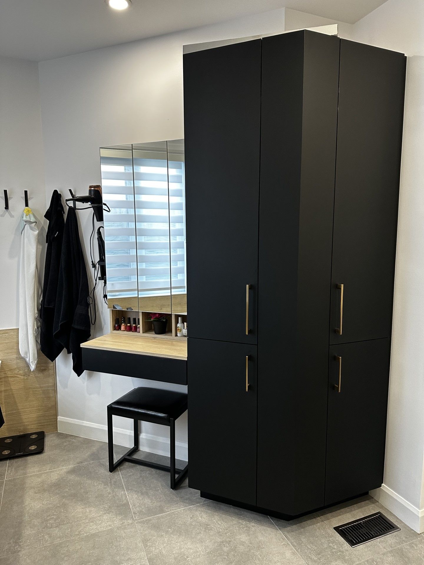 Une chambre avec une grande armoire noire et une coiffeuse.