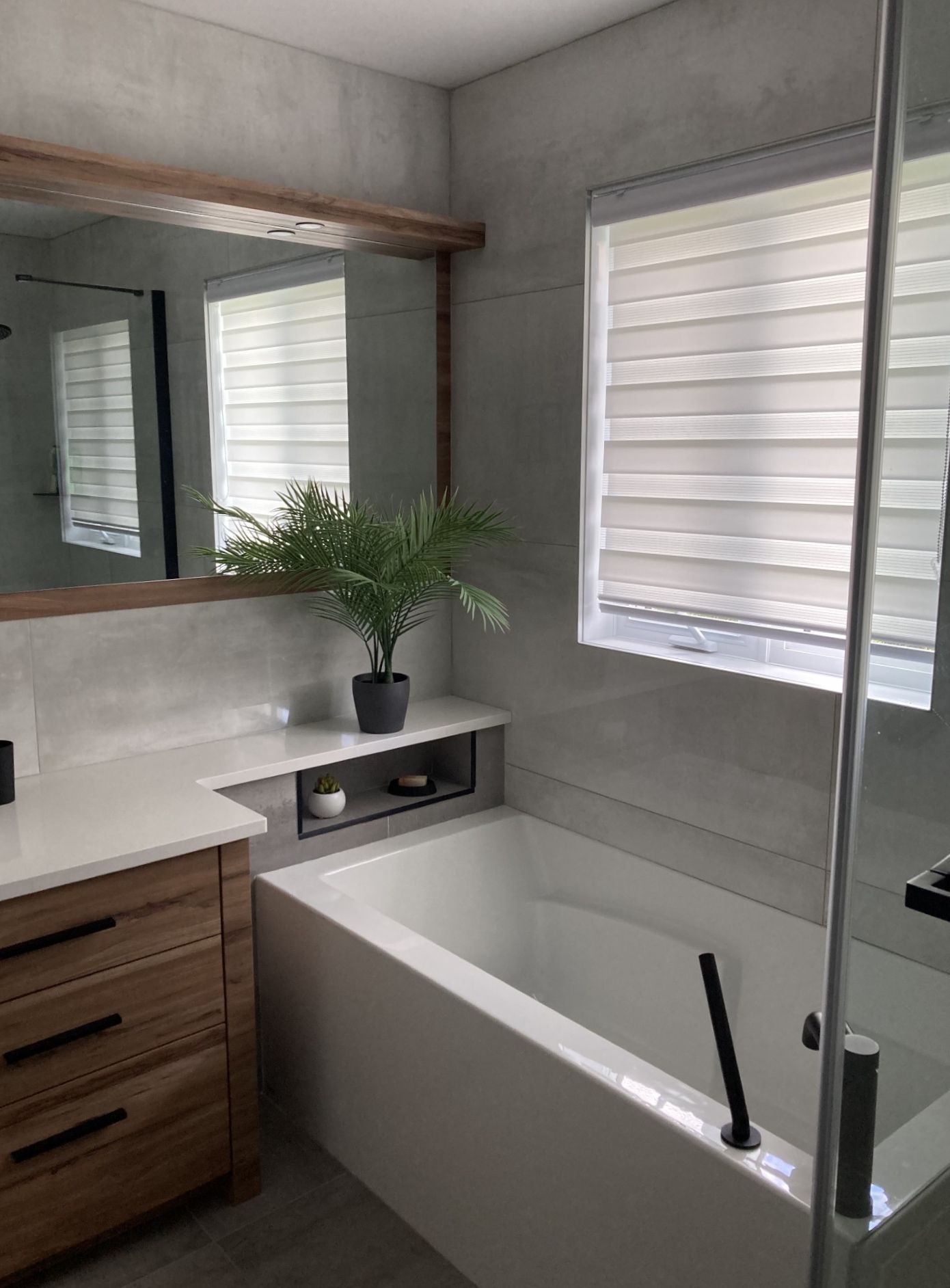 Une salle de bain avec baignoire, lavabo, miroir et fenêtre.