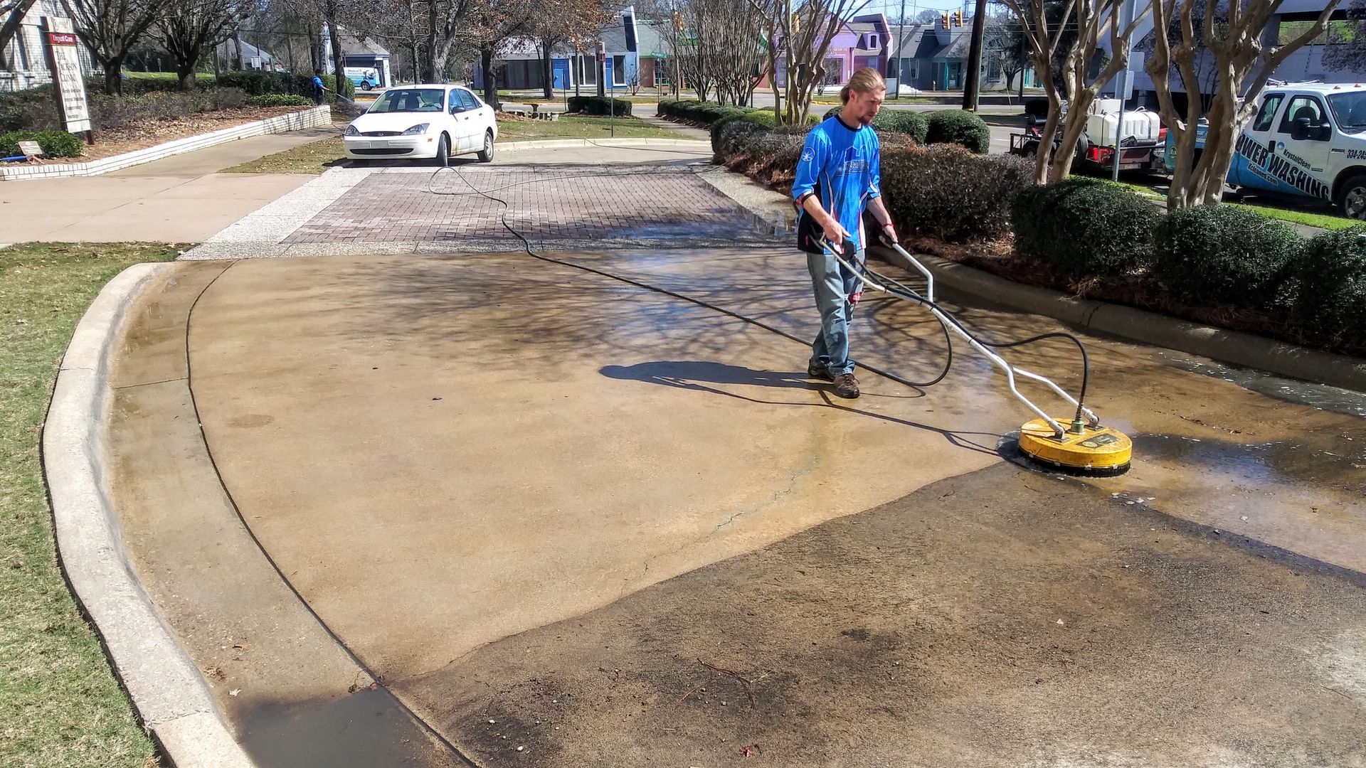 A man is using a pressure washer to clean a driveway.
