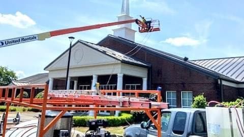 A man is using a crane to clean the roof of a church.