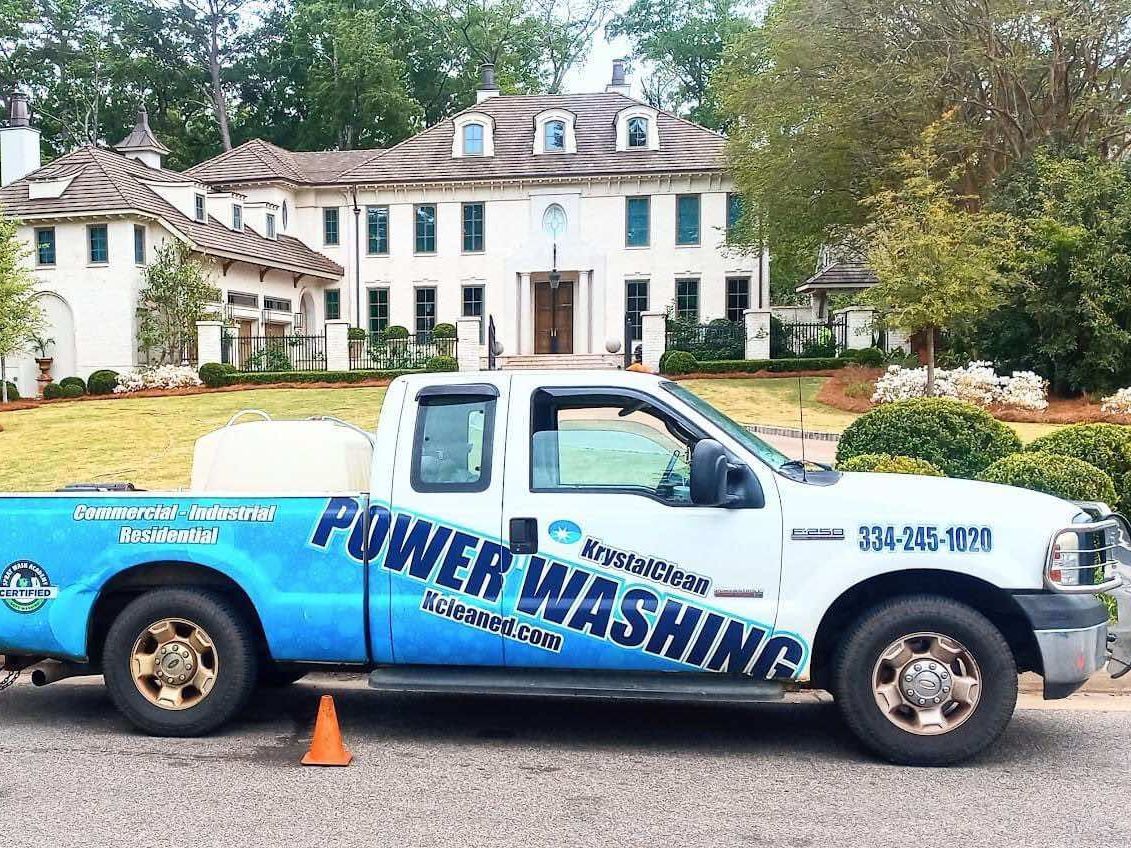 A power washing truck is parked in front of a large house.