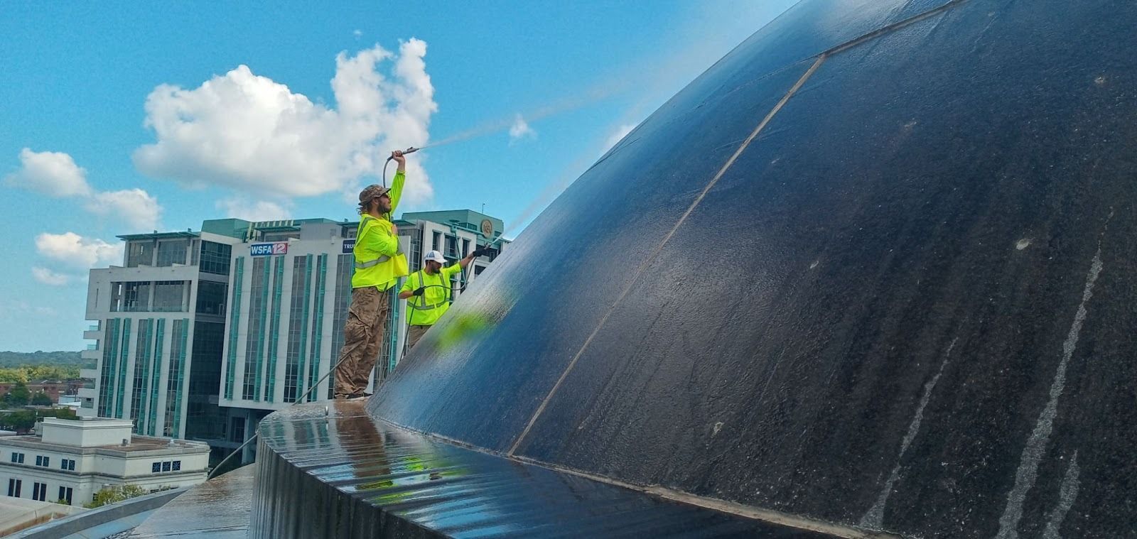 Professional pressure washing crew cleaning a large commercial building exterior to remove grime and