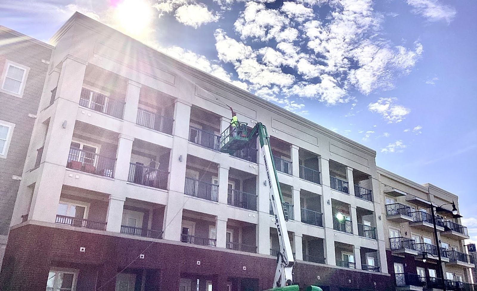 Professional pressure washing of a multi-story commercial apartment building using a lift for exteri