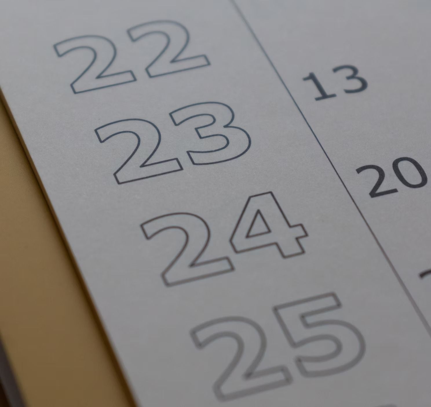 A close-up of a calendar page showing large, outlined numbers 22 through 25, with partially visible numbers 13 and 20.