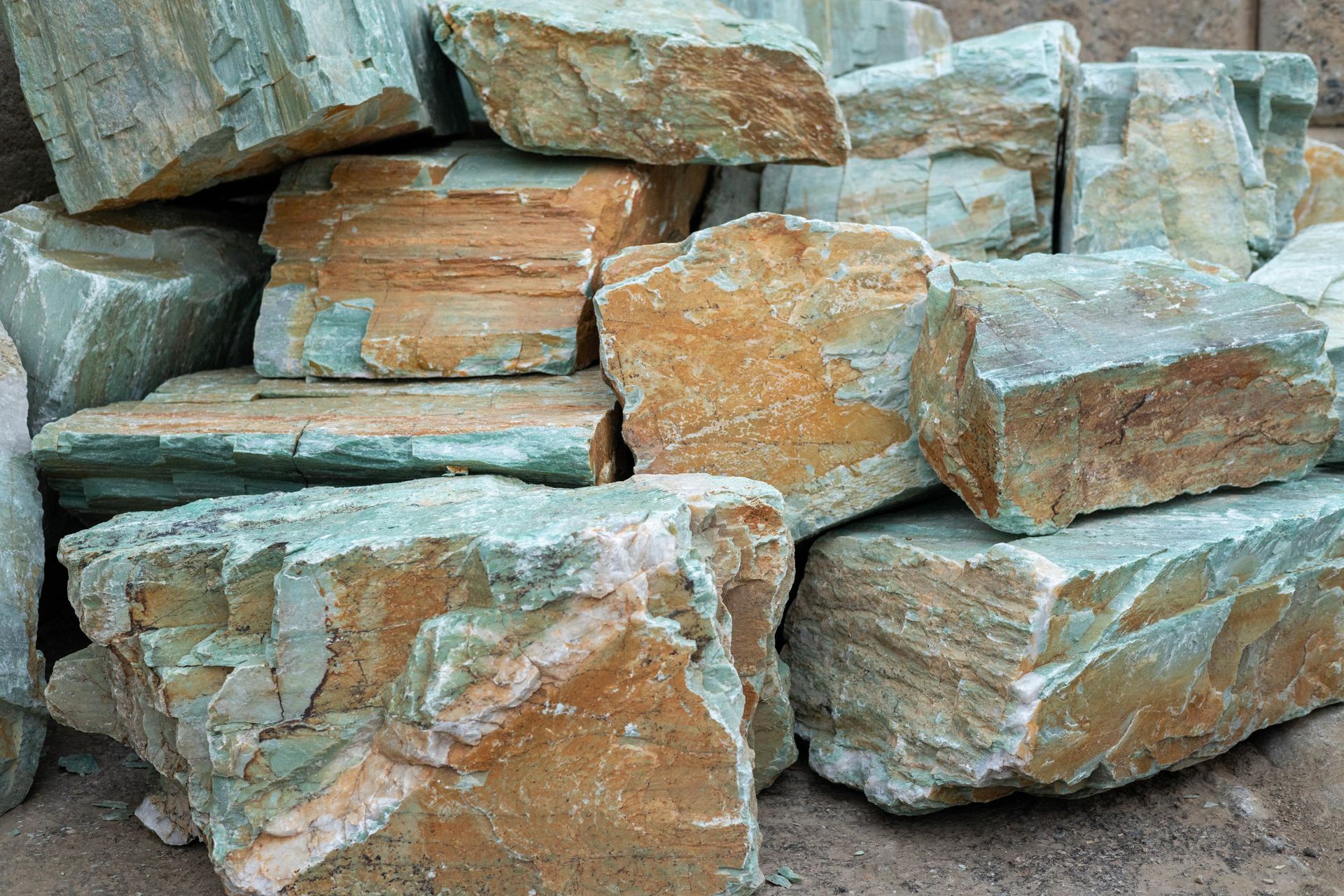 Stacked gray and tan stone blocks on dirt ground