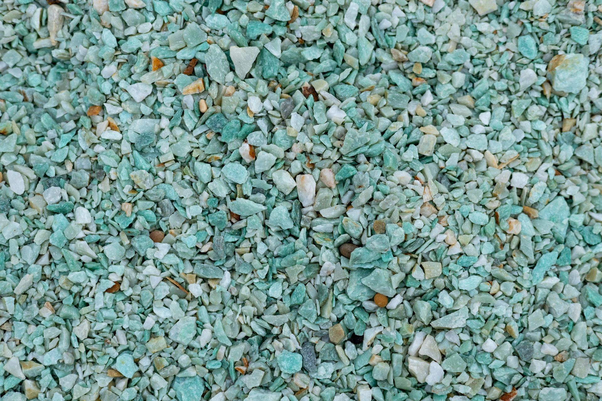 Pile of small green, gray, and tan stones or gravel chips filling the frame