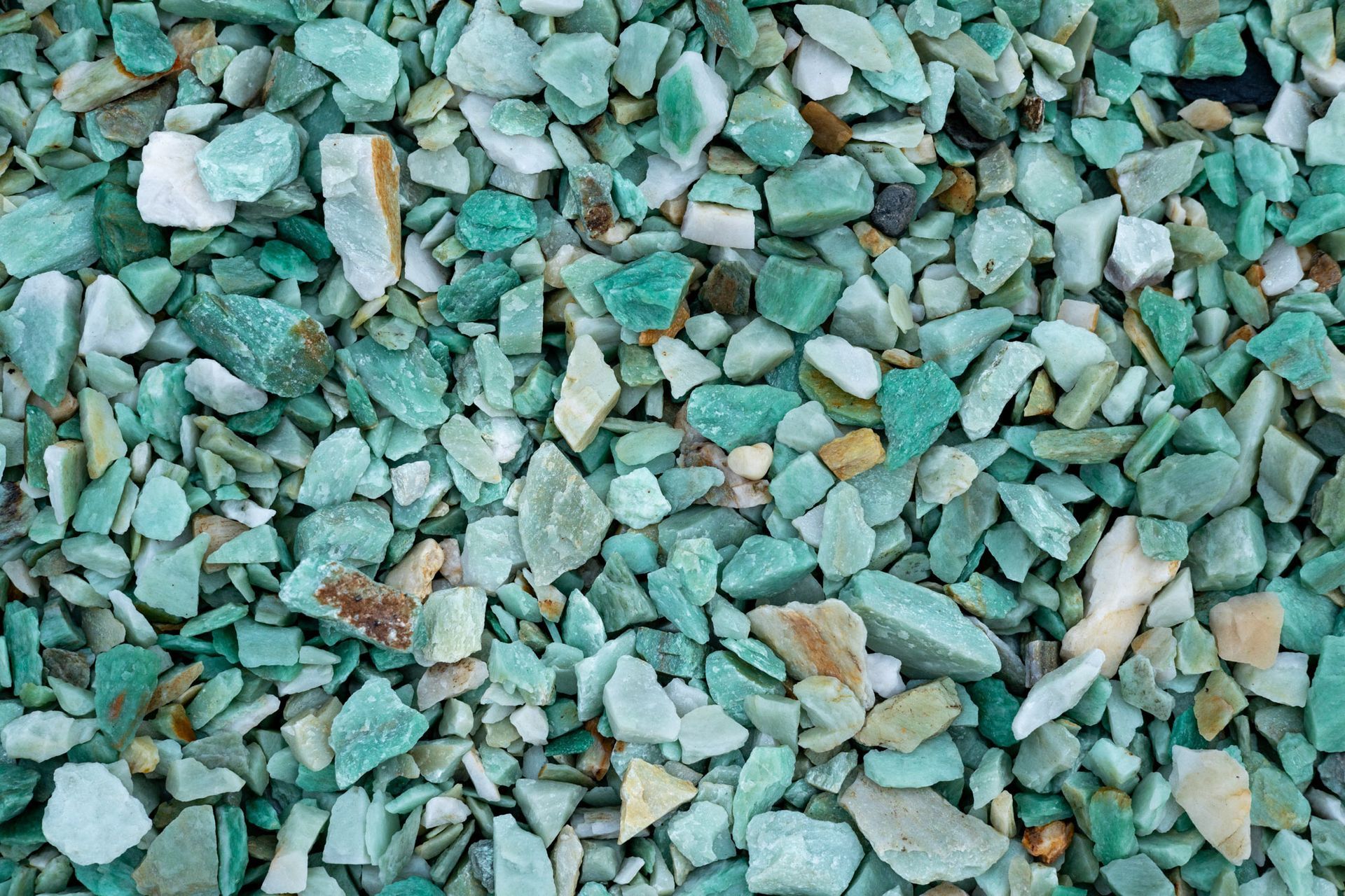 Pile of small green, gray, and tan stones or gravel chips filling the frame