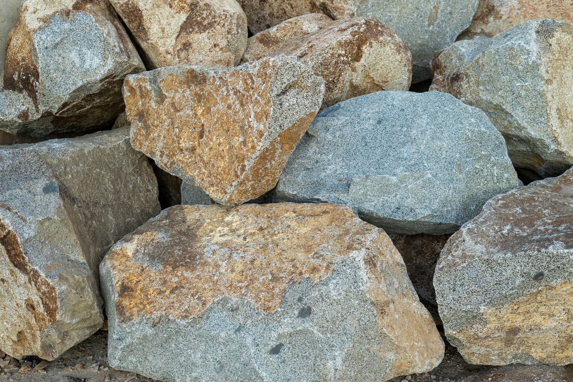 Close-up of rough gray rocks with tan lichen or rust-colored patches stacked together.
