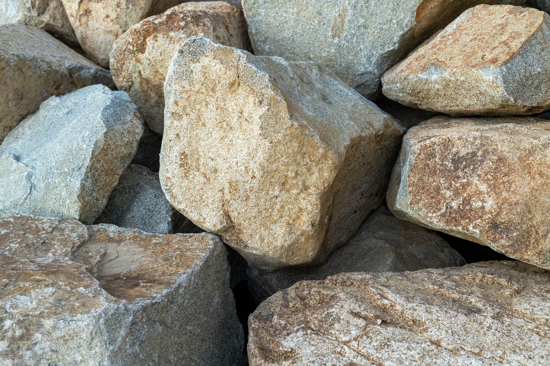 Close-up of rough gray rocks with tan lichen or rust-colored patches stacked together.