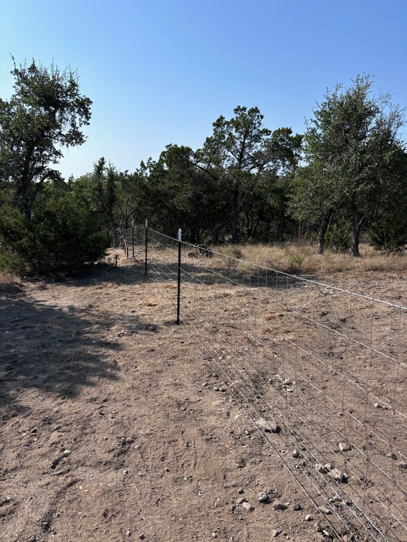 A dirt field with trees in the background and a volleyball net in the middle.