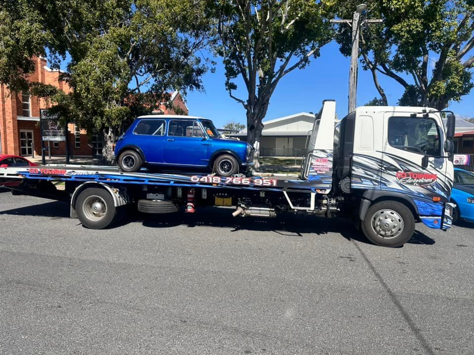 Blue Mini Cooper Car on A Flatbed Tow Truck on A Street — Cq Towing Services In Rockhampton City, QLD