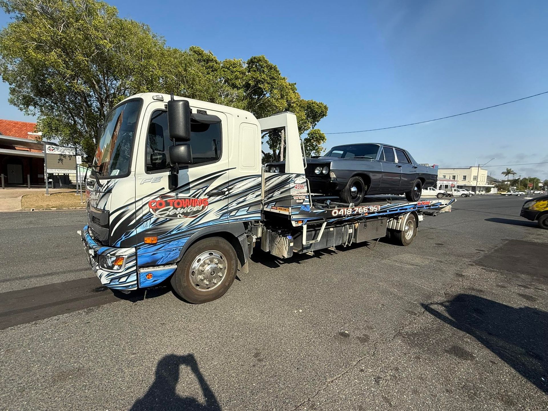 Three trucks with blue and white designs parked in front of a garage under a blue sky.