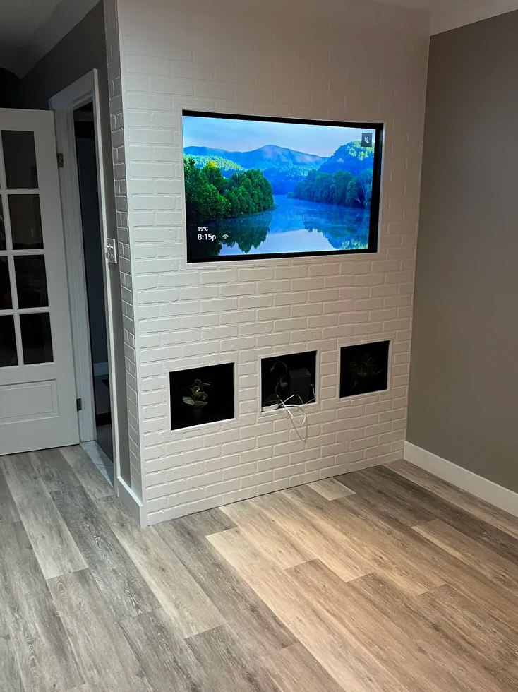 Un salon avec une télévision à écran plat fixée au mur.