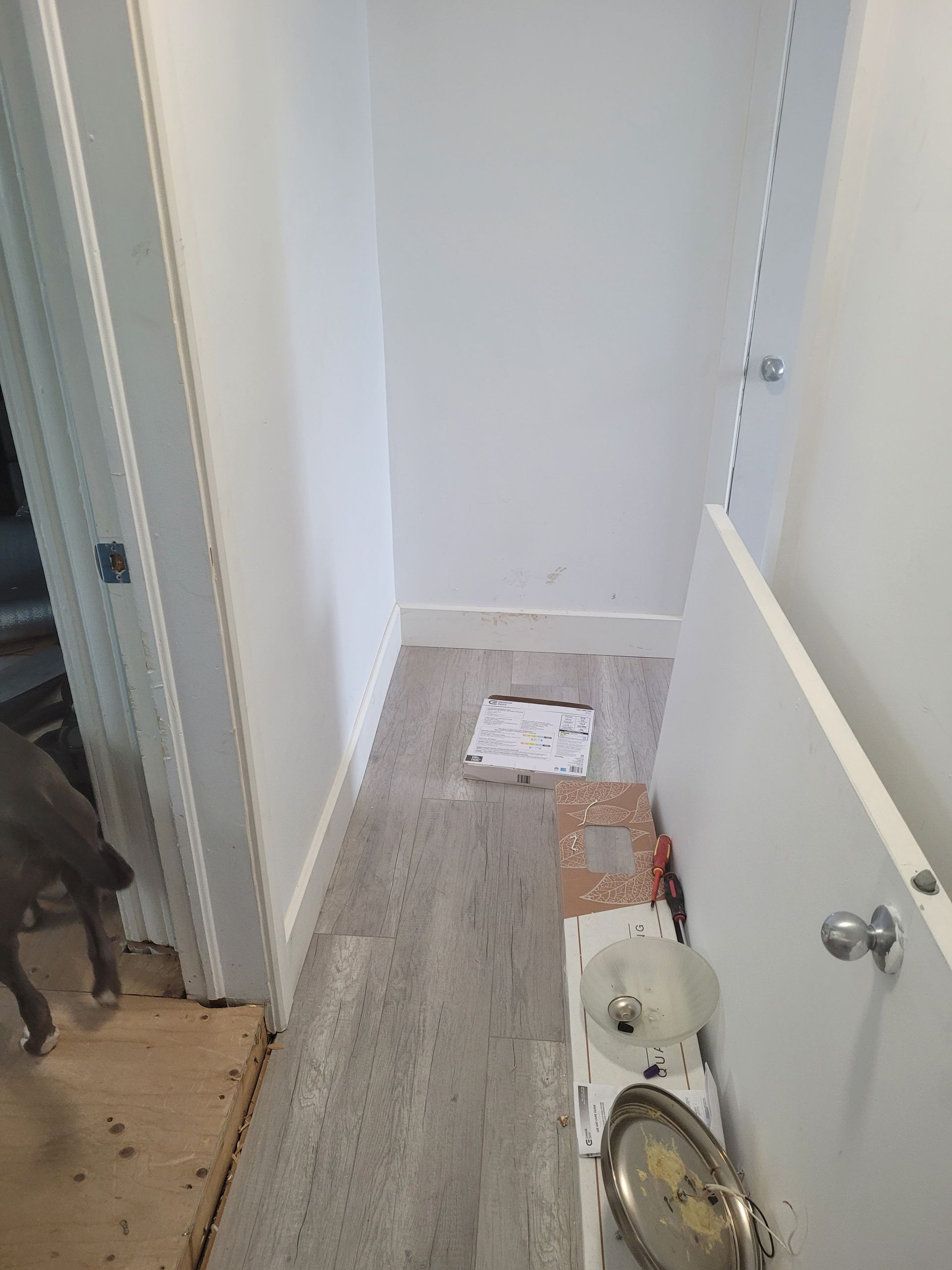 Un couloir avec parquet et murs blancs.