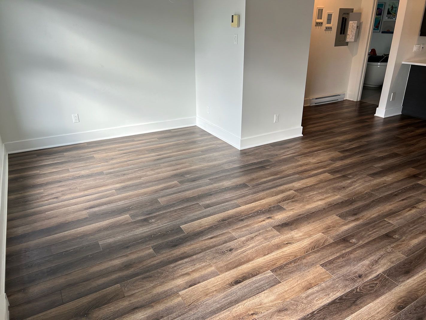 Un salon avec parquet et murs blancs.
