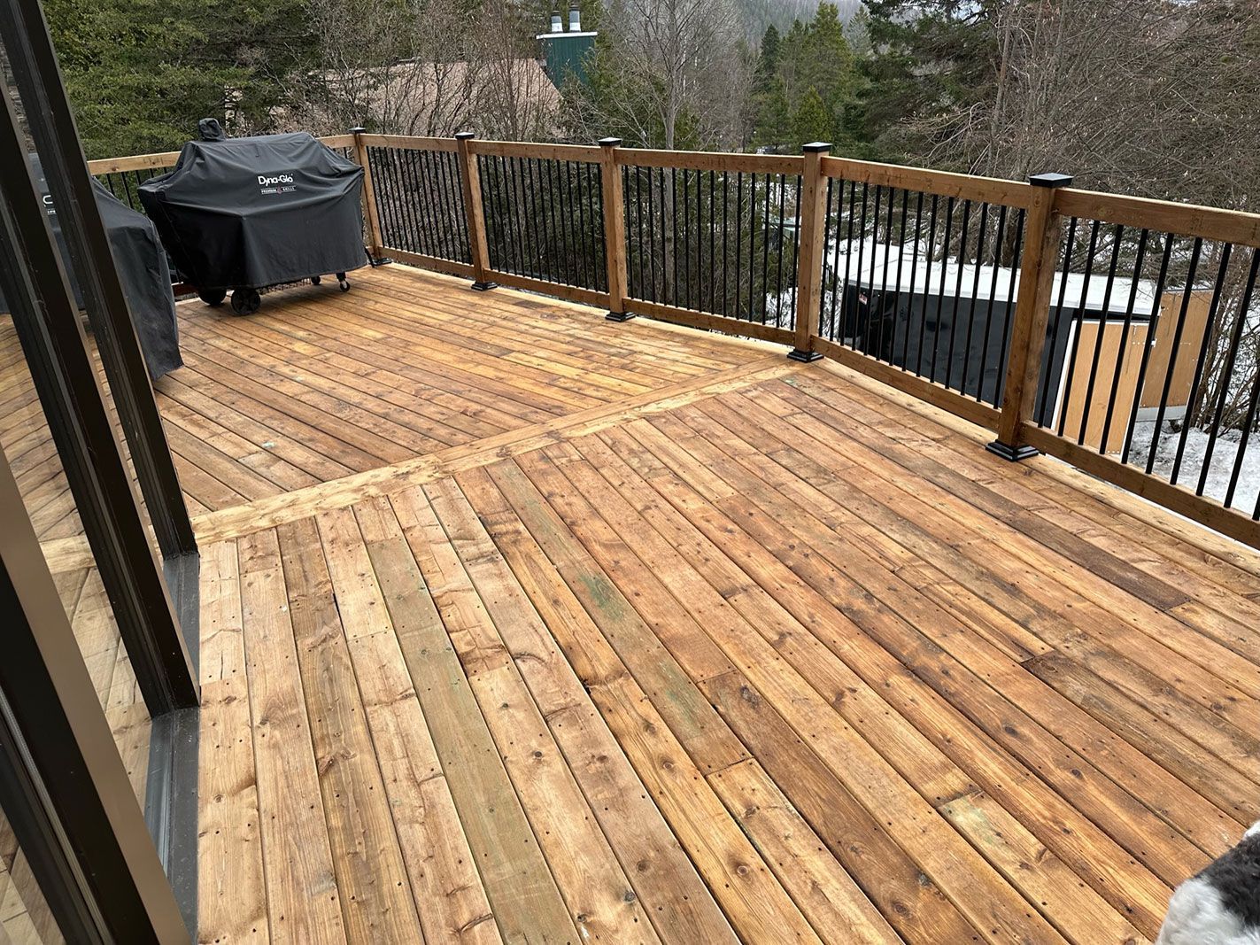 Une terrasse en bois avec une balustrade noire et une grille dessus.