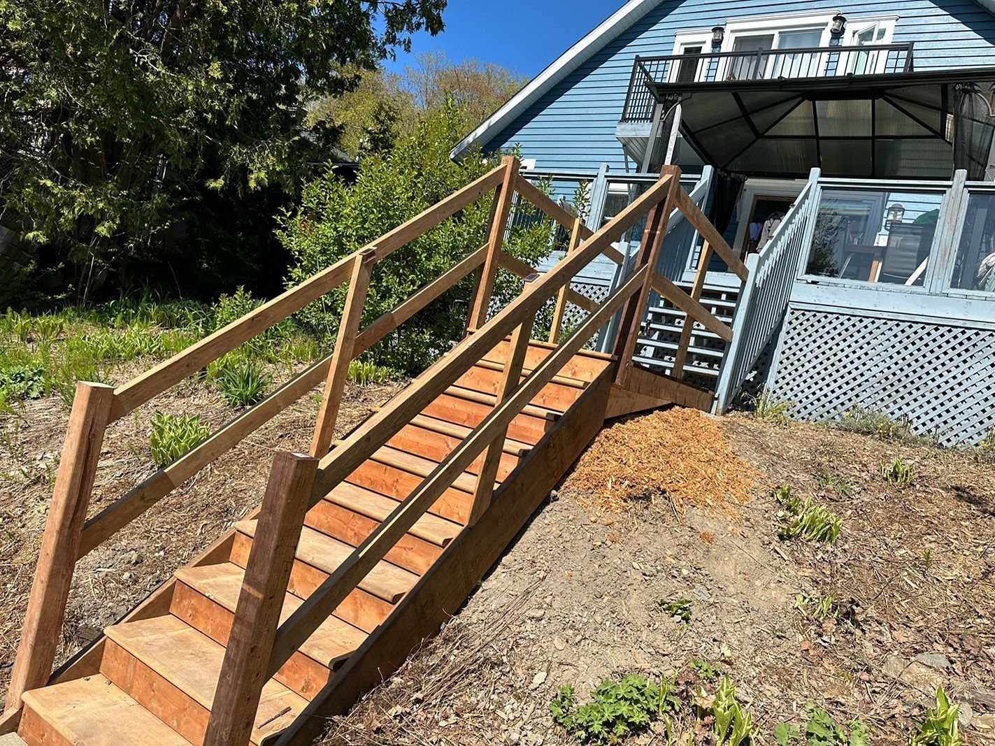 Une rampe en bois avec des escaliers menant à une maison.