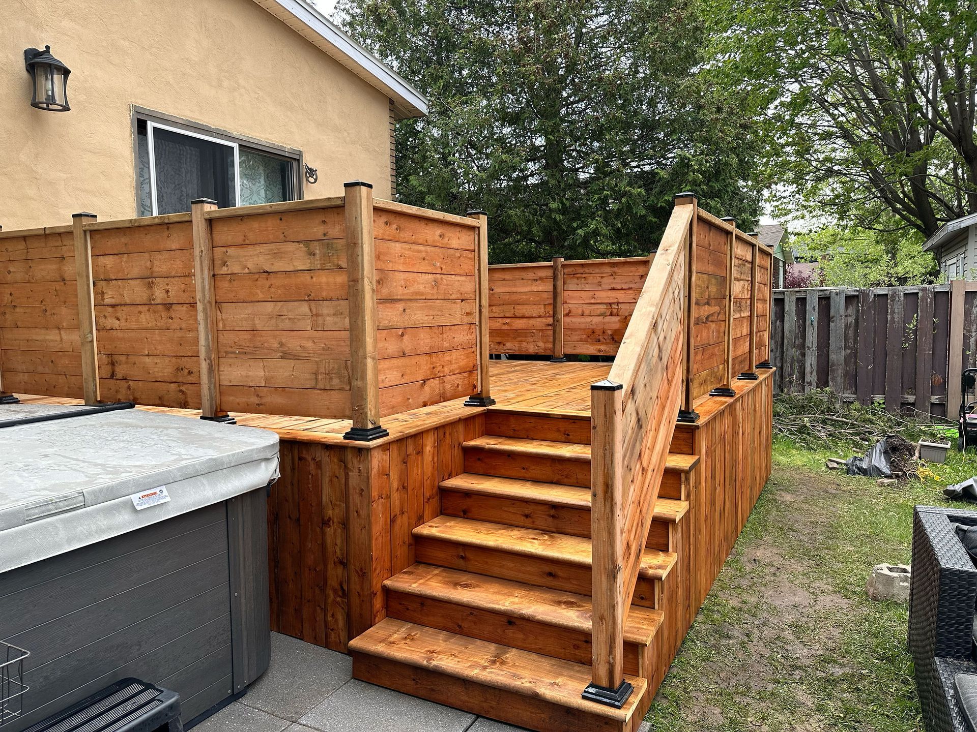 Une terrasse en bois avec des escaliers et un bain à remous dans l'arrière-cour d'une maison.