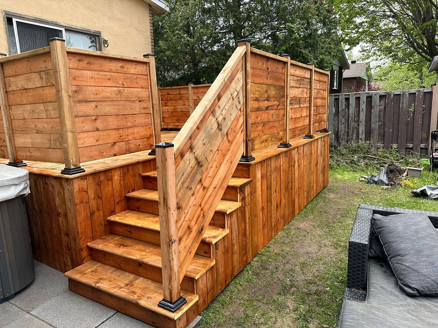 Une terrasse en bois avec des escaliers et une clôture dans une cour arrière.