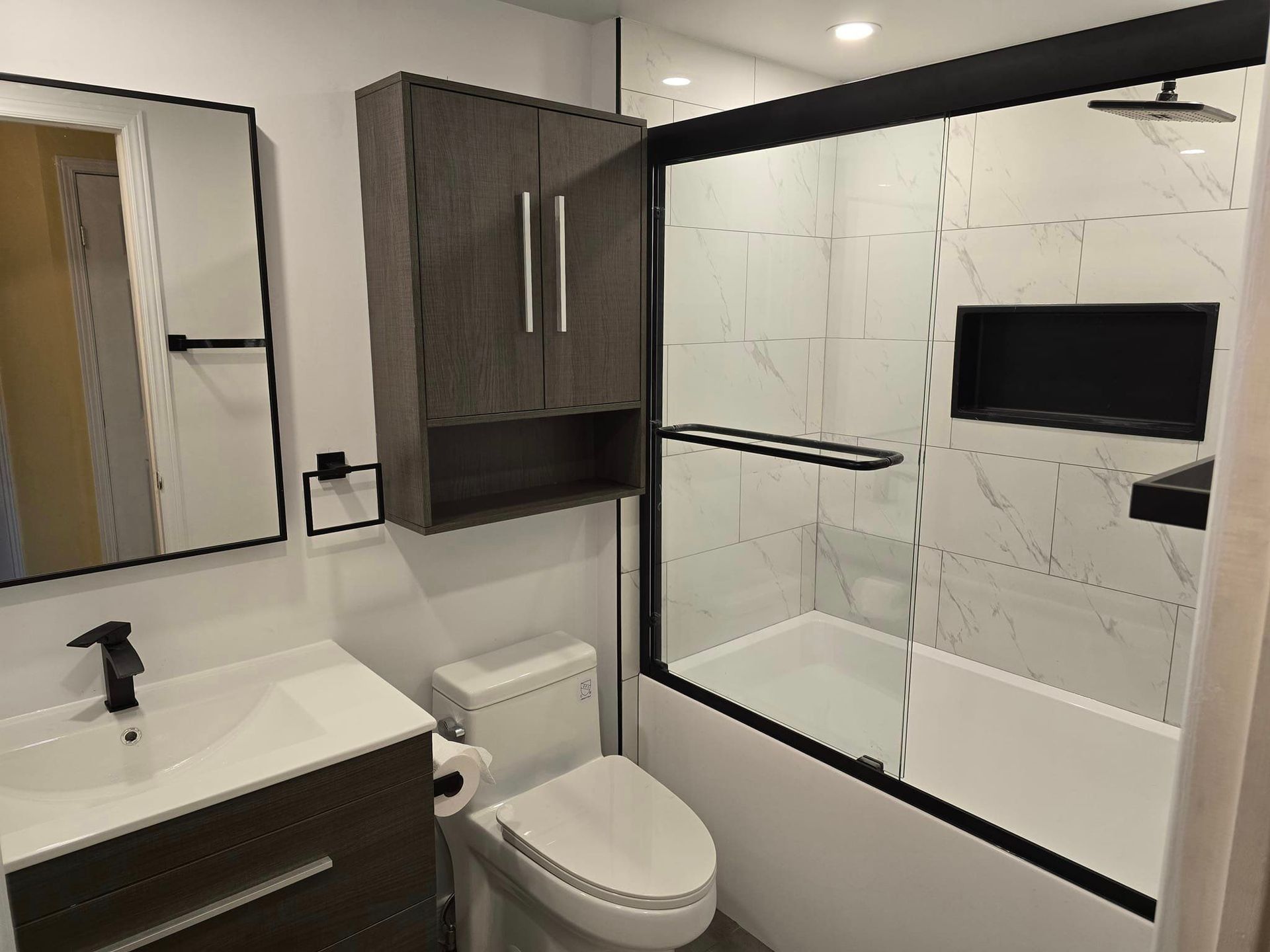 Une salle de bain avec WC, lavabo, miroir et baignoire.