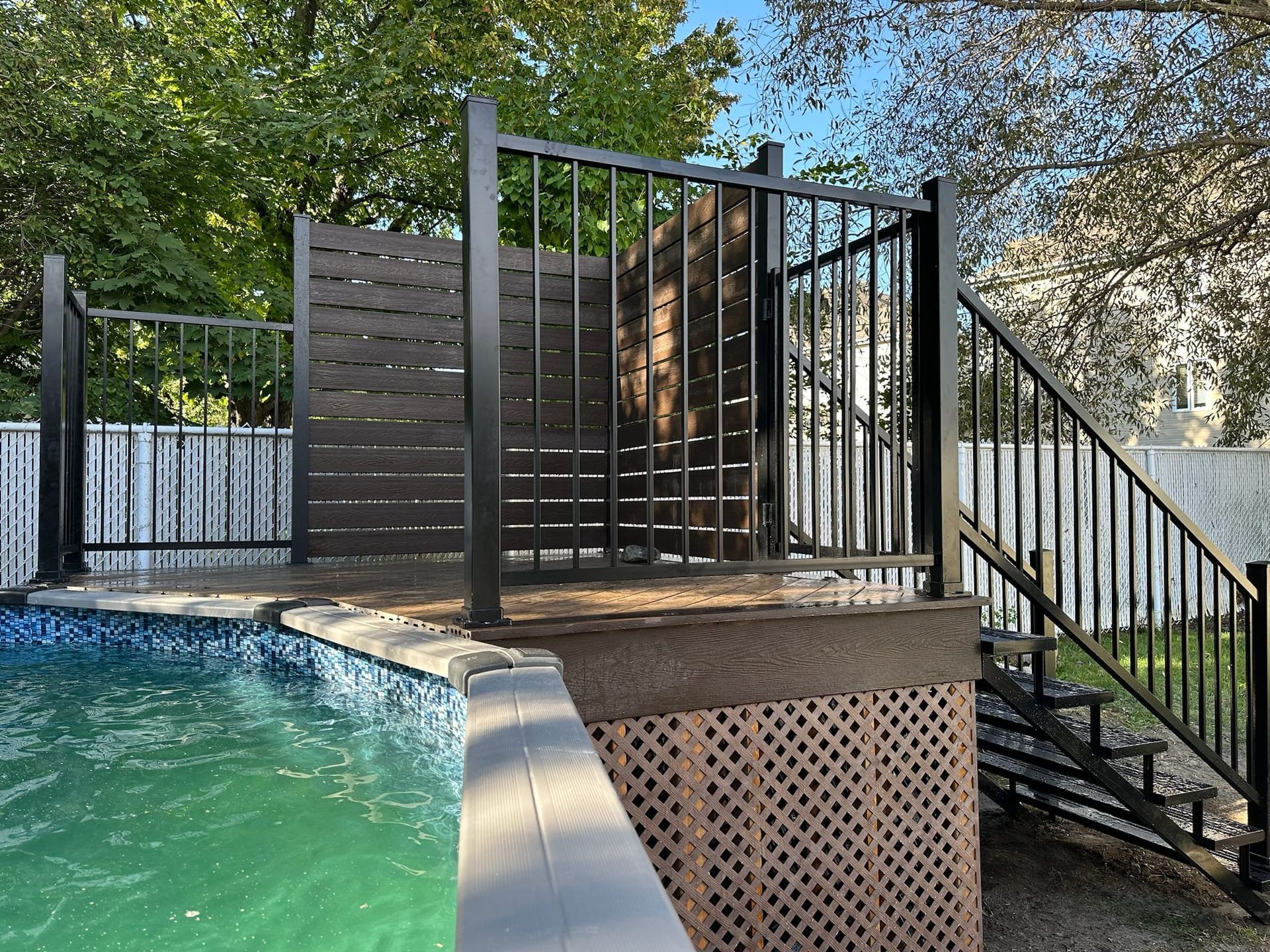 Une piscine avec une terrasse et des escaliers à côté.